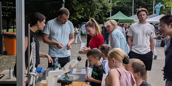 Besucher am Stand mit Destille, Mikroskop und Fangplatten