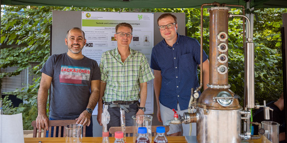 Dr. Marco Aras, Jörg Fischer and Dr. Georg Hubmann at the BCI stand with a distillation apparatus